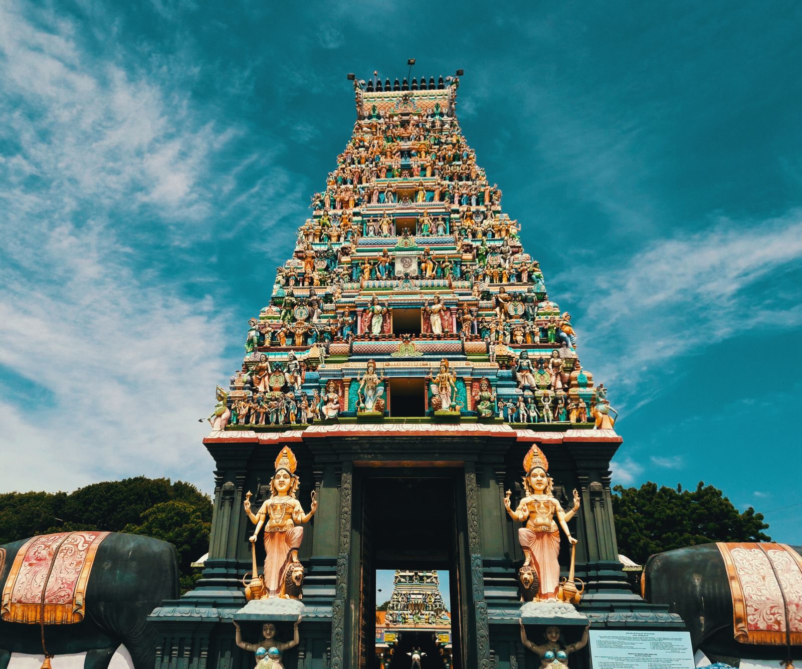 A temple with intricate carvings on its roof and two hindu deities on either side of the entrance