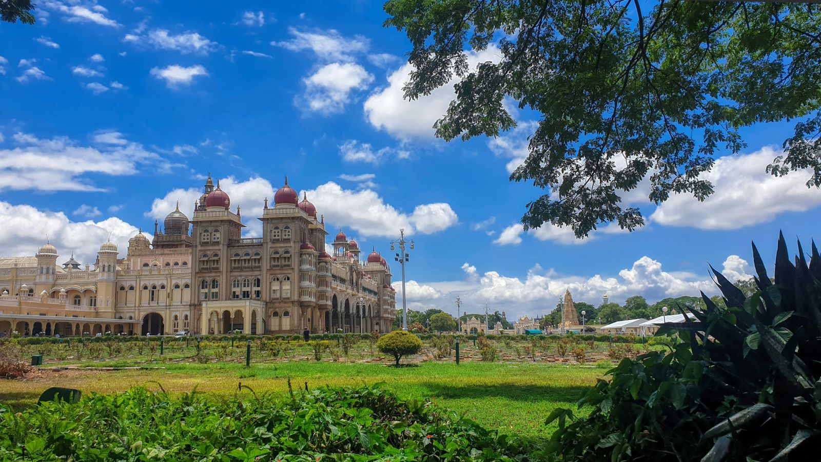 A far out view of the mysore palace with a manicured garden in the foreground