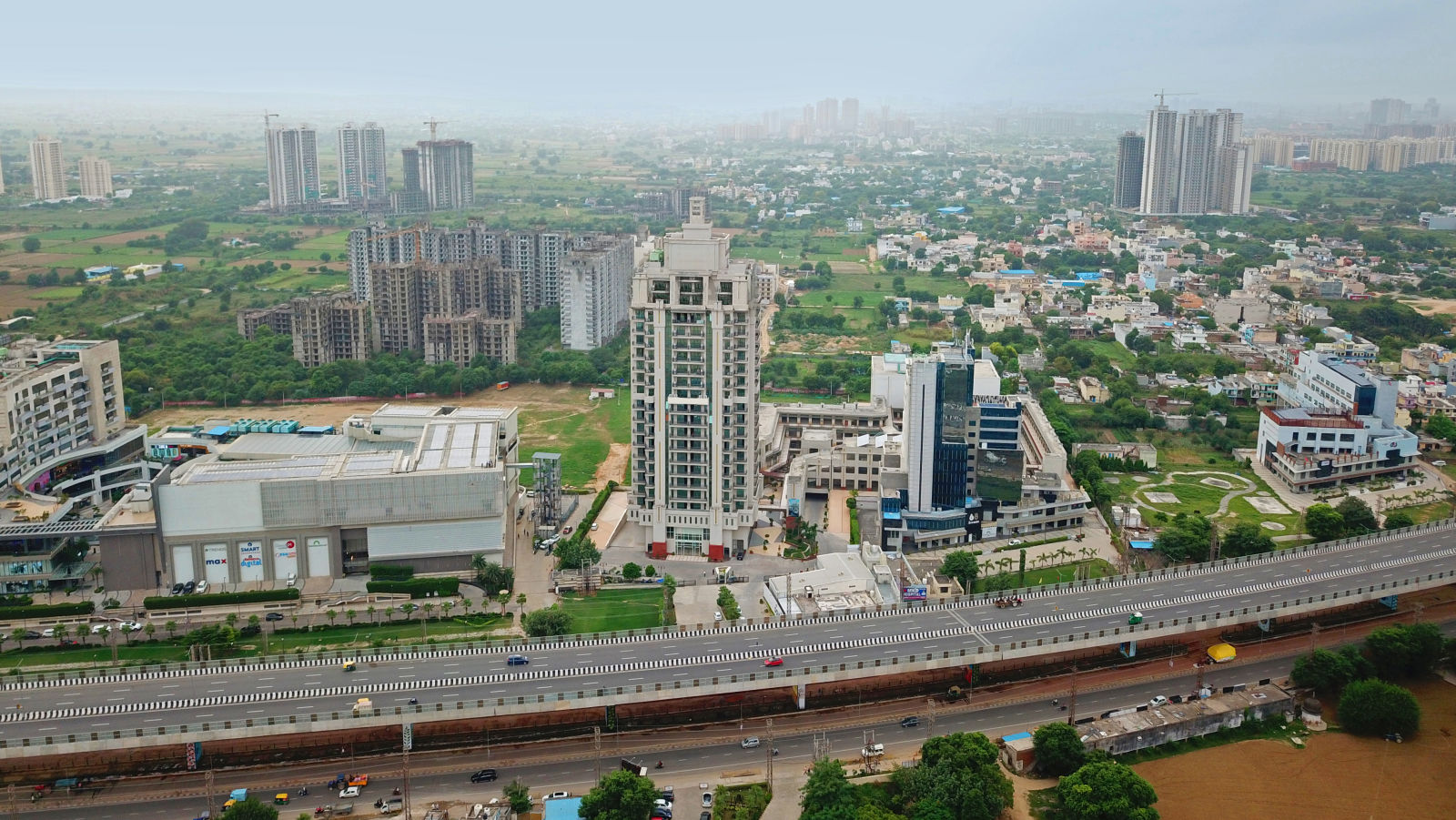 Bird's eye view of Rhythm Gurugram with other buildings and trees next to it 