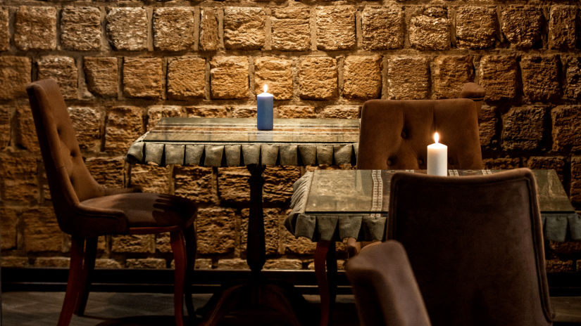 a stone walled restaurant with top lighting and dining table set for eating