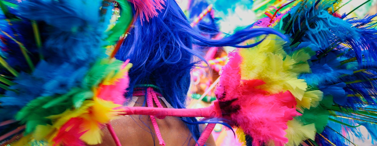 A woman having decorative feathers attached to her clothes during a carnival