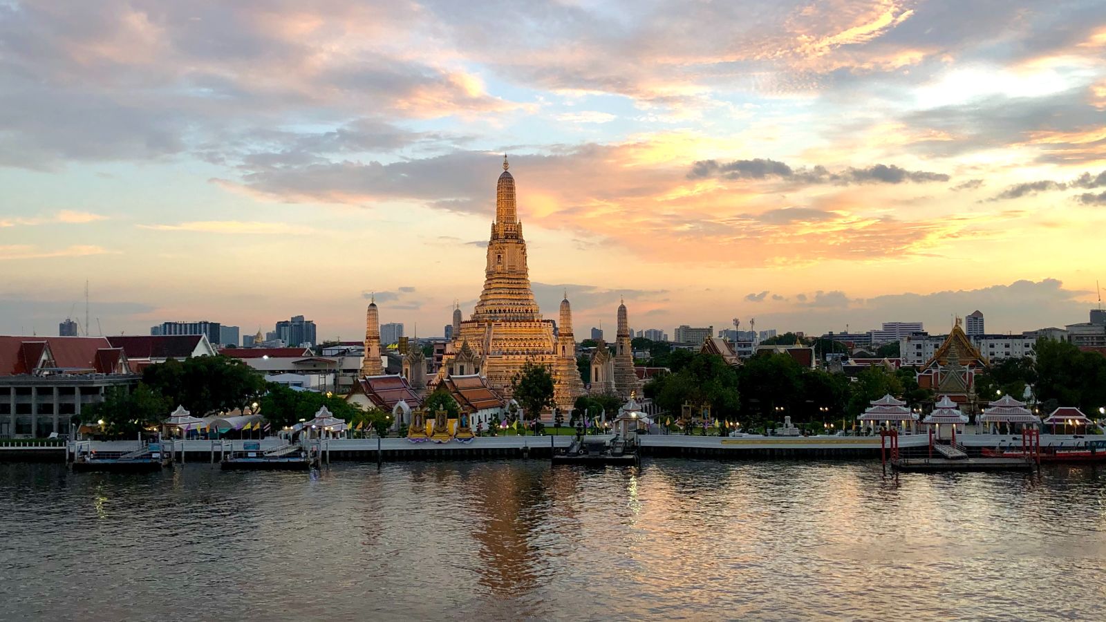 a temple in gold colour situated in front of the river front with buildings text to it