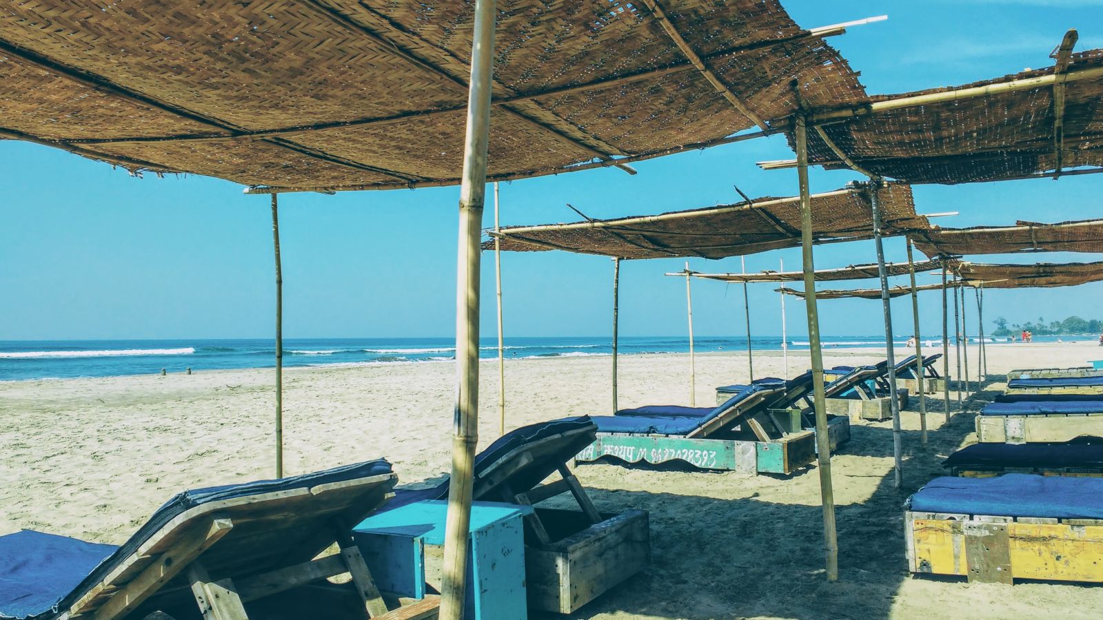 beach shacks with sunbeds under it on the beach