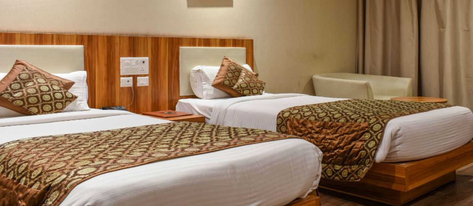 corporate room with twin beds and warm lighing at le roi raipur hotel