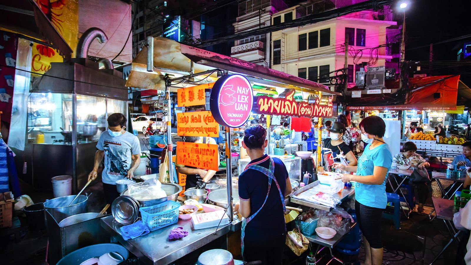 a person buying food from a vendor selling street food in Bangkok