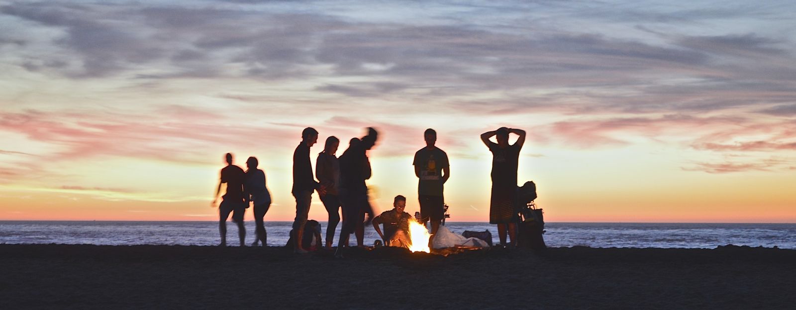 a group of people enjoying a bonfire by an ocean