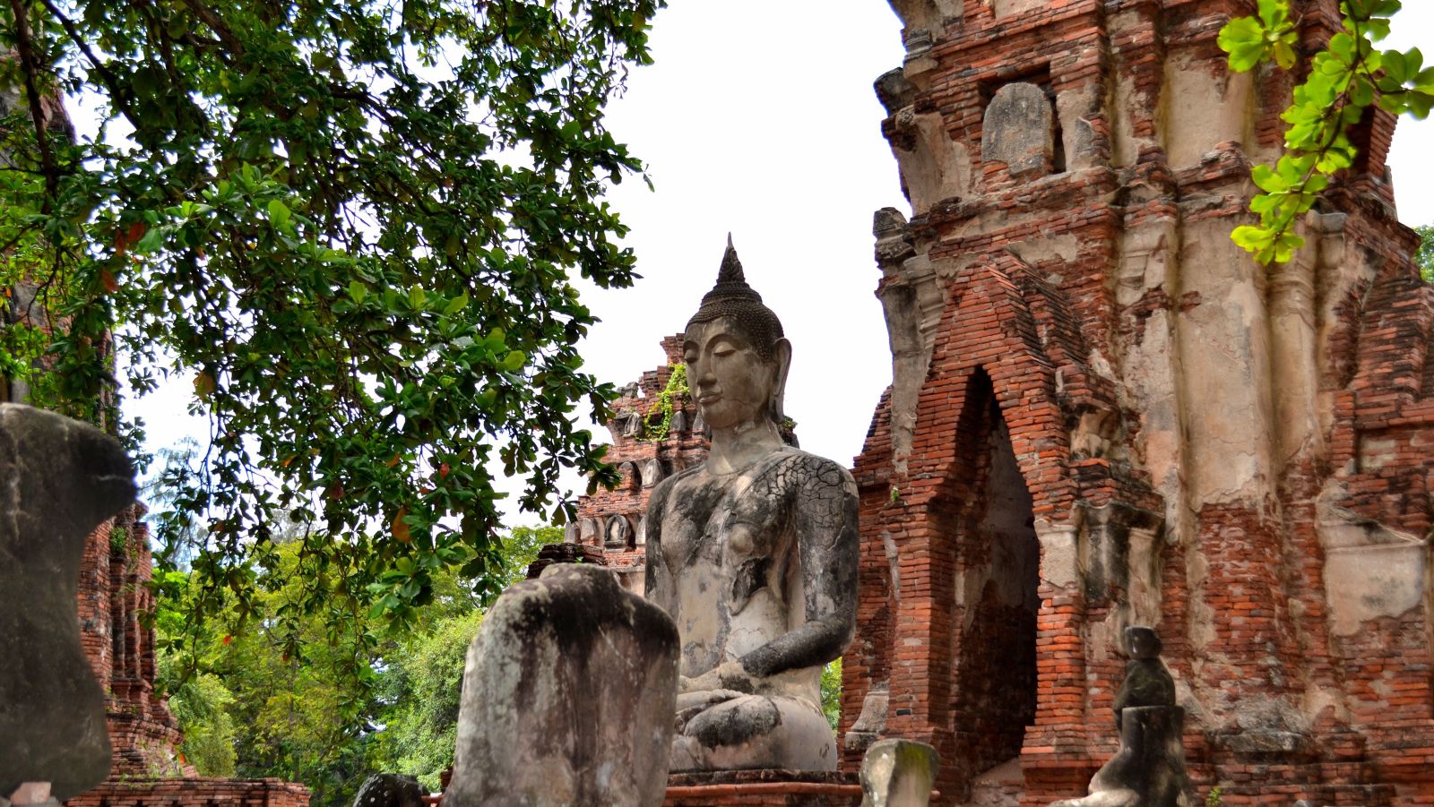 a buddha statue amidst ruins during daytime