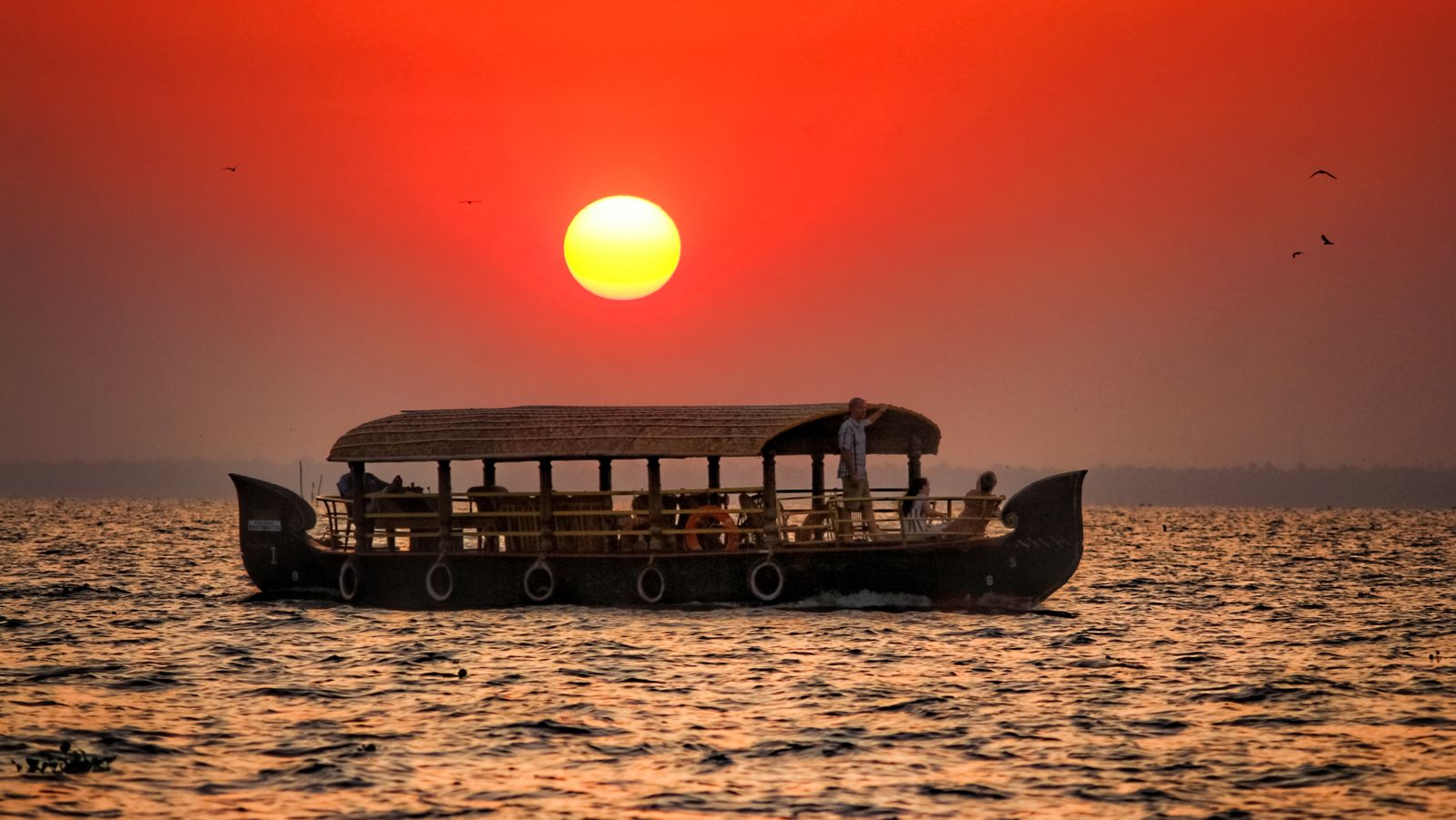 a solitary boar travelling on a lake in Kumarakom with the sun setting in the background