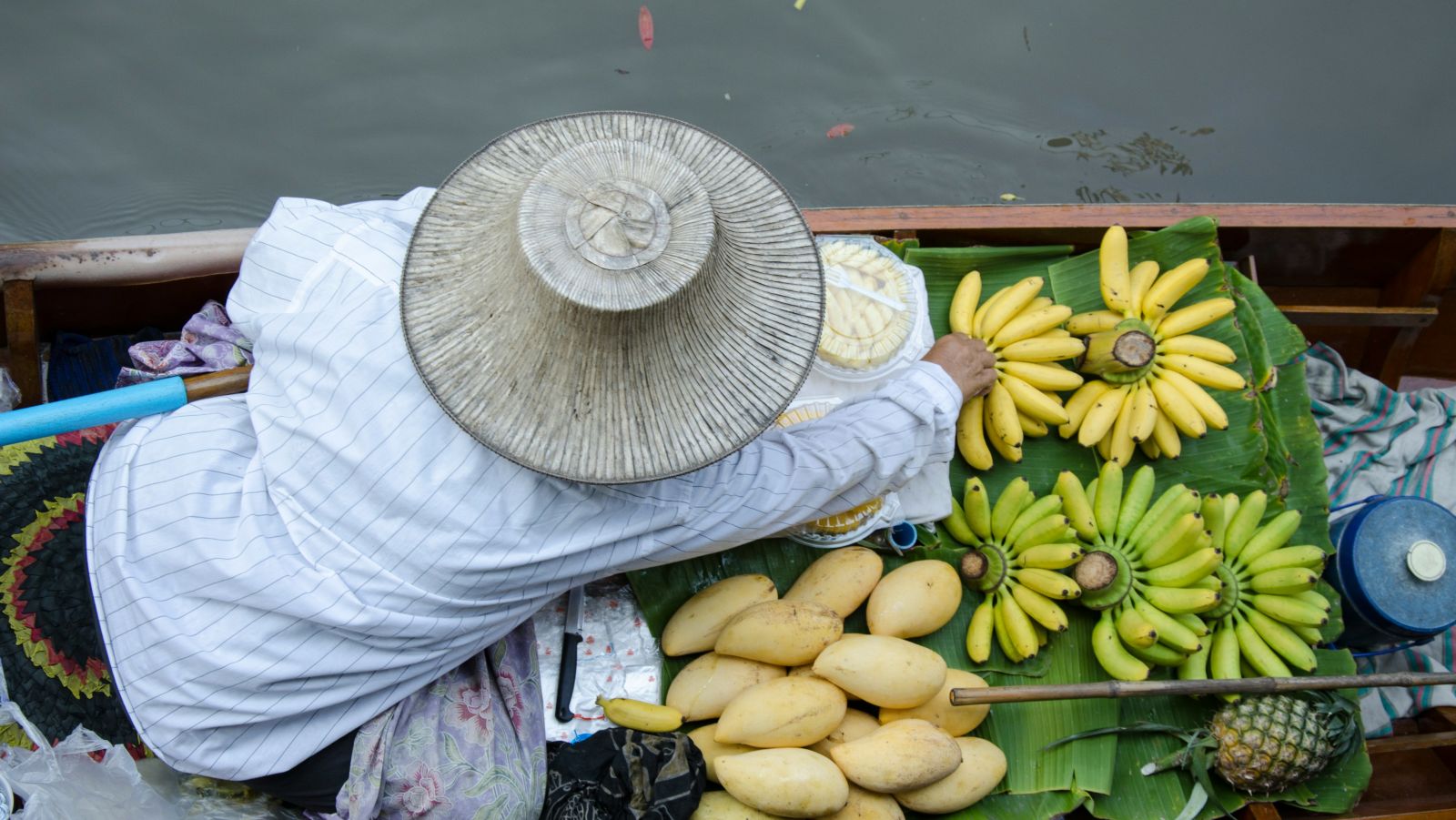 a person keeping bananas and other fruits before a sale in a floating market