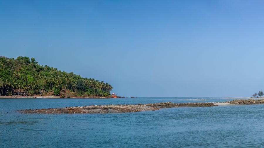 A view of a beach and a land filled with trees in the background