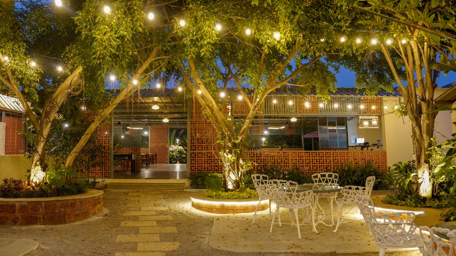 An image a restaurant with outdoor seating, bright lighting, greenery and decoration - Trance Veechika Resort