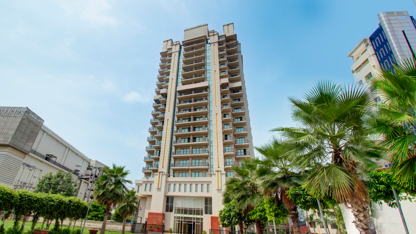 Facade view of the Entrance to Rhythm Gurugram with trees and paved road leading to the hotel - Hotel Booking in Gurugram