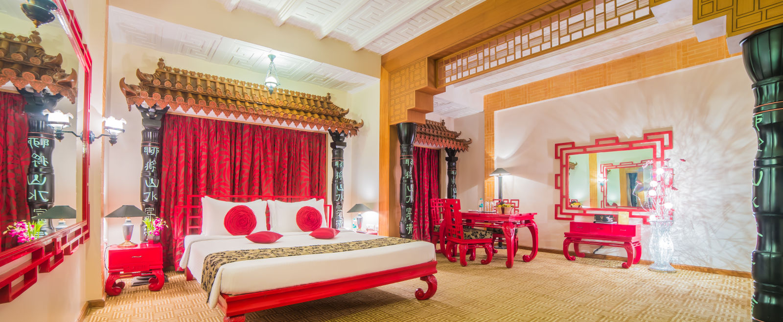 A grand hotel suite with an opulent red and white decor, large bed, and seating area, reflecting a traditional style at Sitara Luxury Hotel in Hyderabad near Ramoji Film City.