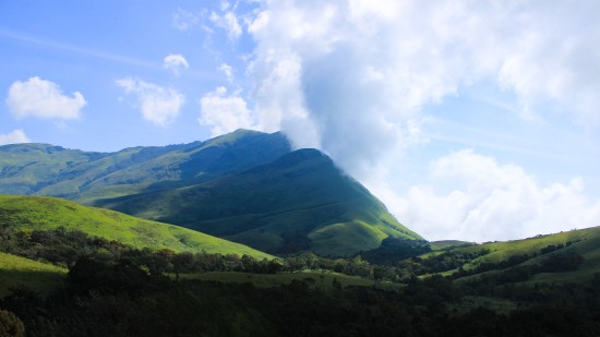 view of lush green hills with a cloudy sky during daytime