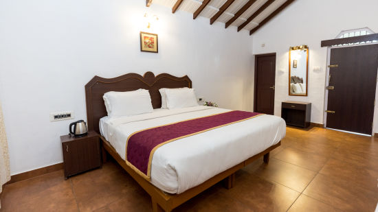 A king bed inside the deluxe double room - Capitol Village Resort, Madikeri