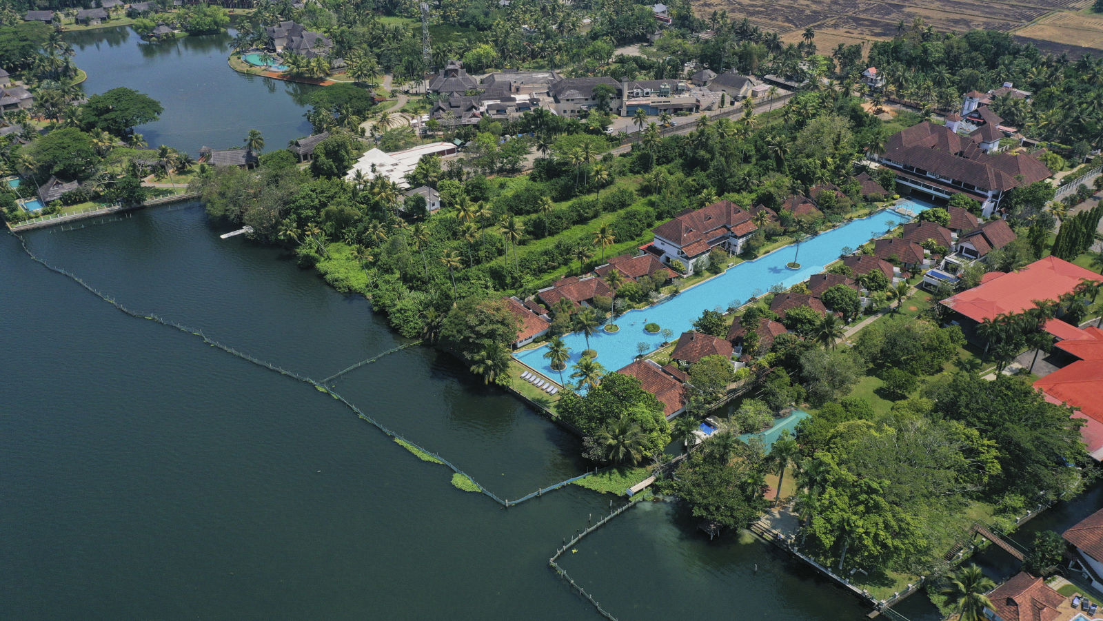 Bird's-eye view of a luxury resort nestled by a lake, surrounded by rich greenery- Kumarakom