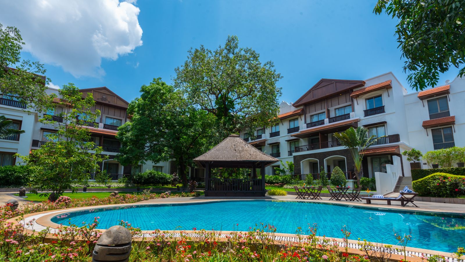 Swimming pool in front of a white resort building - Rhythm Lonavala