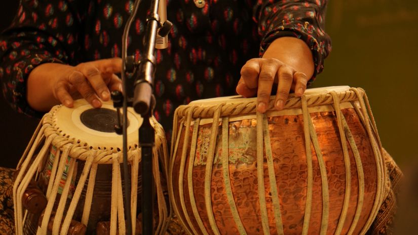 a person playing the table on stage with a mic next to the tablas - Polo Floatel Kolkata