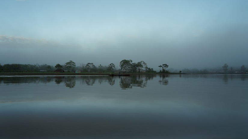 Image of a river in which a baoat containing people is cruising in the distance