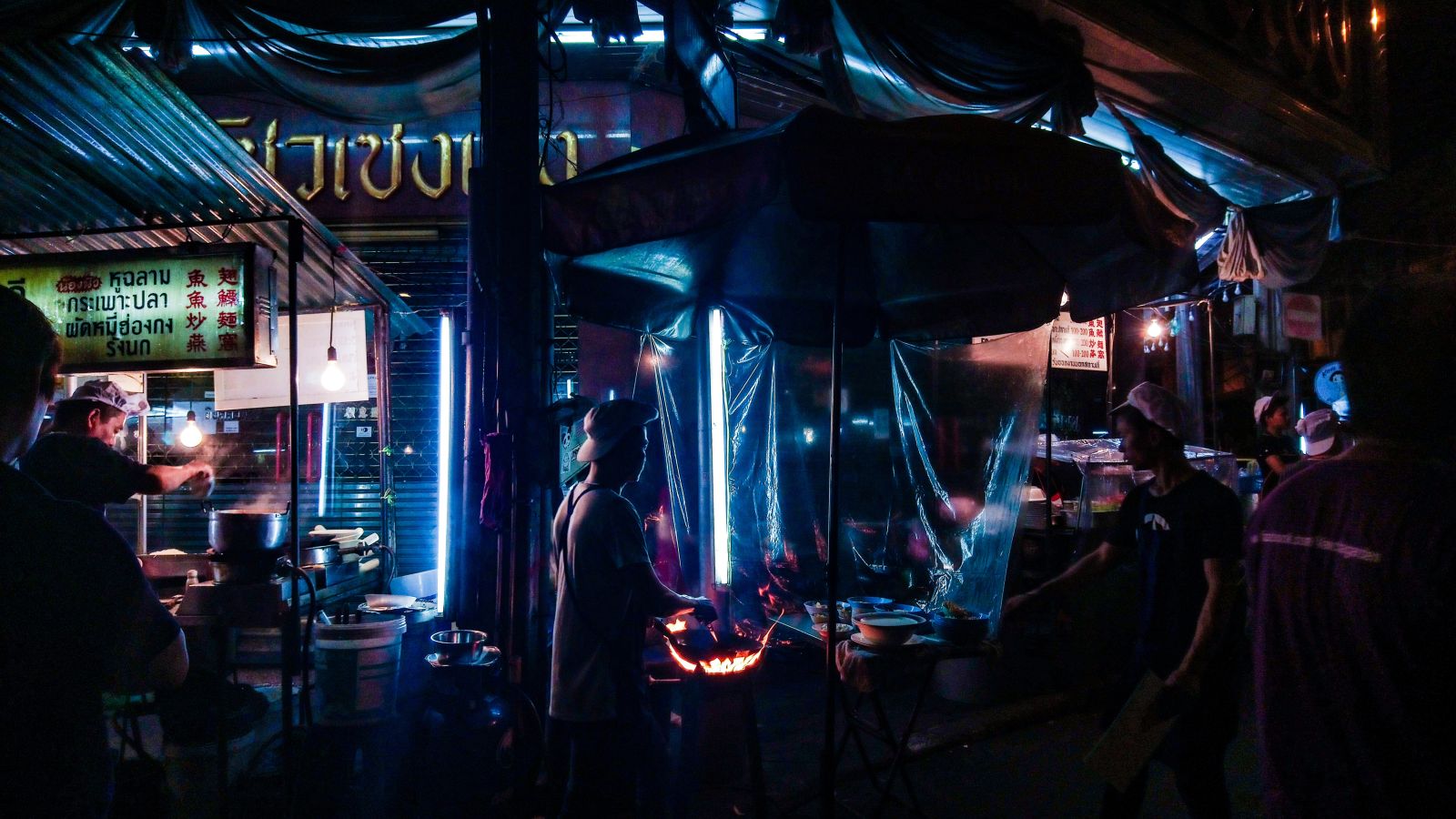 a view of the Yaowarat market in the night where many street vendors are cooking