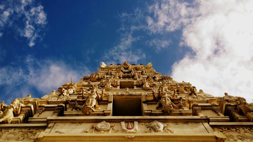 A view from below of a temple with intricate architecture on the wall