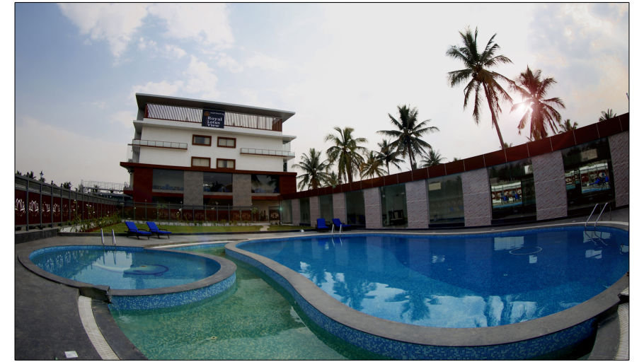 image of a beautiful swimming pool with clear waters surrounded by green trees situated in front of the resort building - Royal Lotus View Resotel