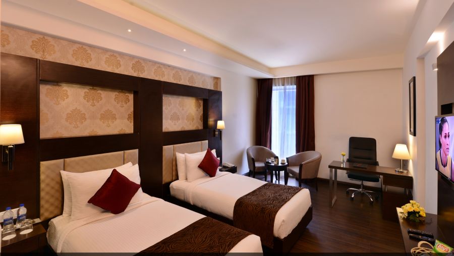 Image of Deluxe Rooms with Twin beds, a TV, chair and table