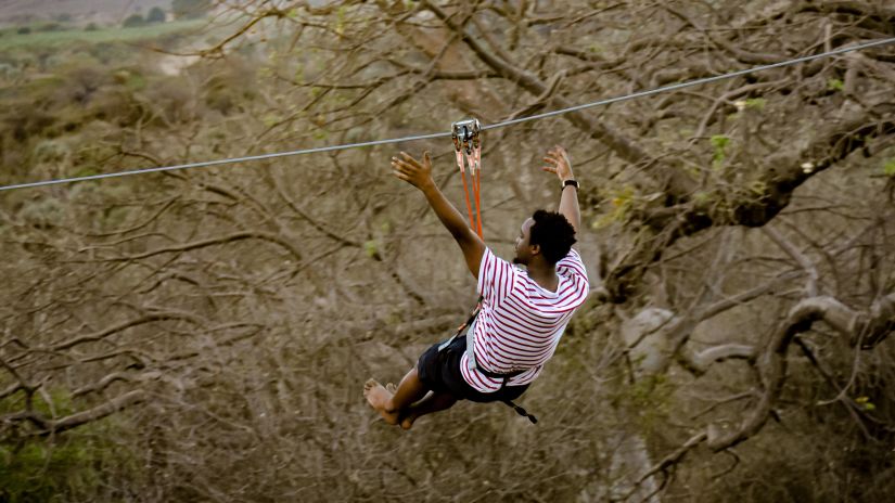 A man enjoys ziplining through the woods - Best vacations near Delhi