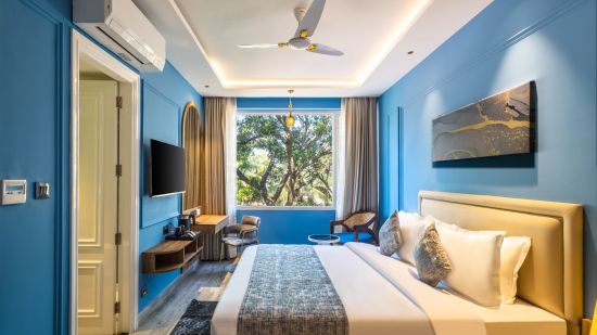 A side view of the bed with bedding in a blue colored room | Renest Calangute, Goa