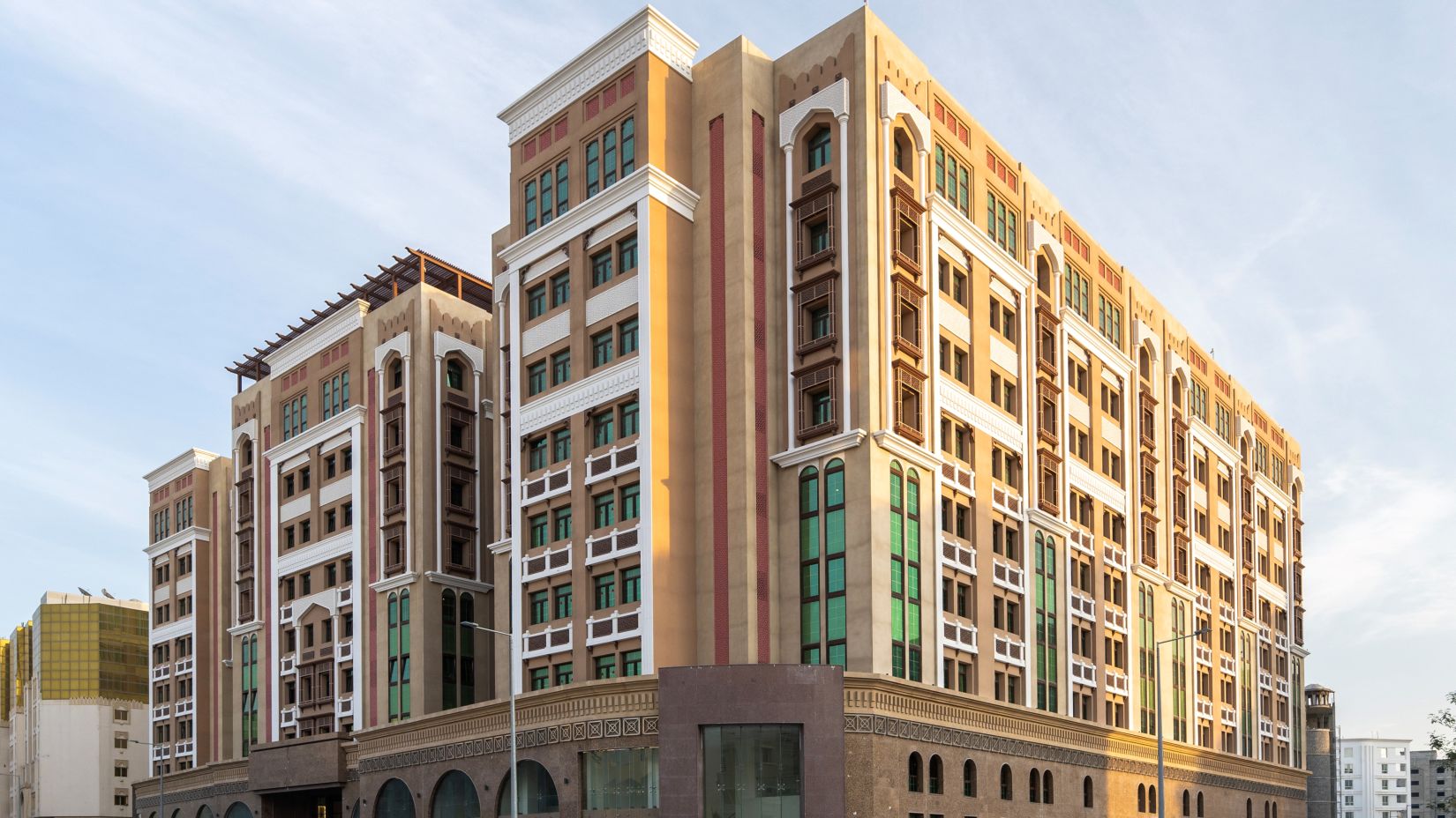 Facade image of La Maison Hotel, Doha with blue sky in the background