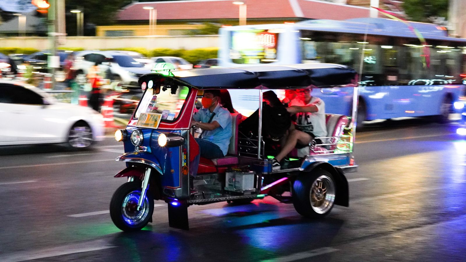 A tuk tuk going on a street of Bangkok with passengers inside