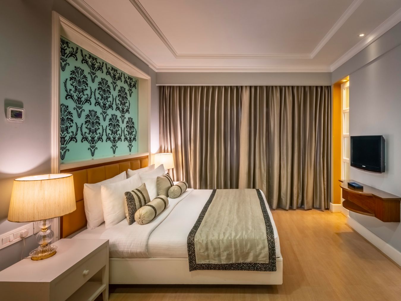 side view of the bed in the Junior Suite with curtains in the backdrop at Kenilworth Hotel, Kolkata