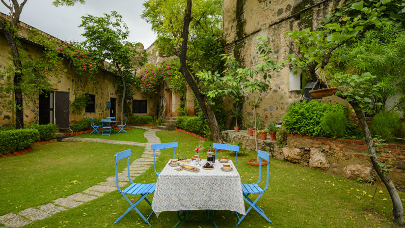 Hill Fort Kesroli 14th Century Alwar - image of a table with chairs on grass adjacent to a pathway