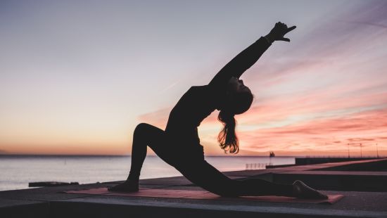 a woman in a yoga pose during sunrise