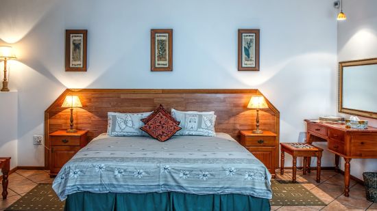 A well lit room with a double bed and a dressing table