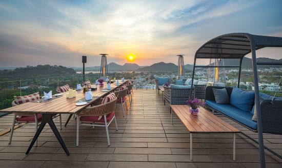 alt-text Seating arrangements on rooftop with a view of the sunset at Parallel Hotel, Udaipur