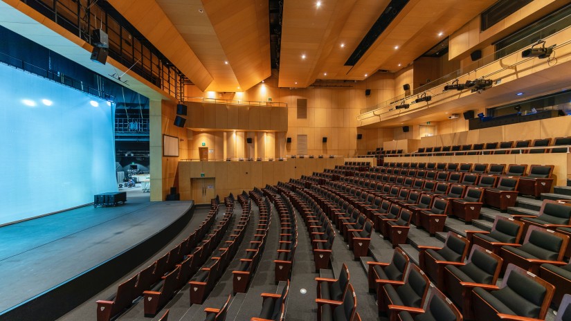 a spacious hall packed with several seat overlooking a screen