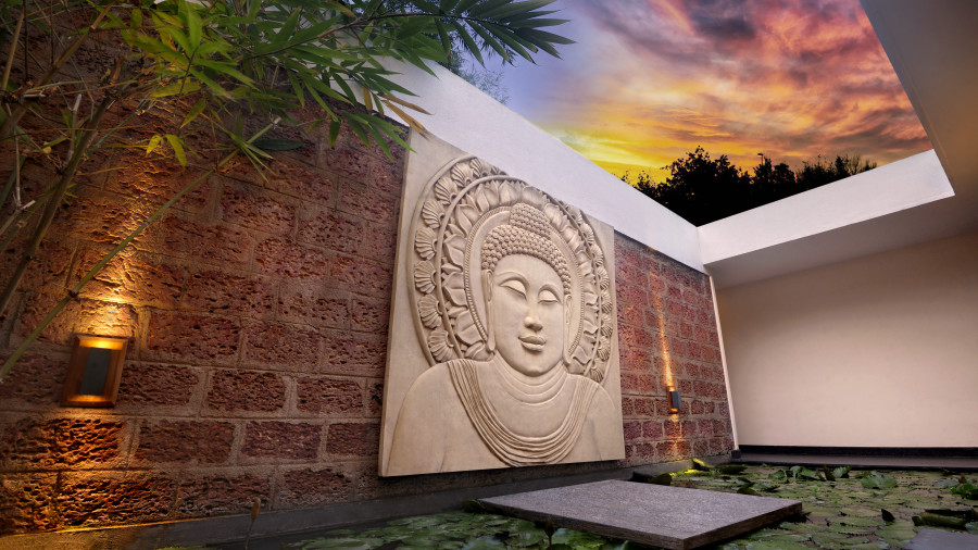 Artistic Buddha wall sculpture with ambient lighting in an outdoor setting.