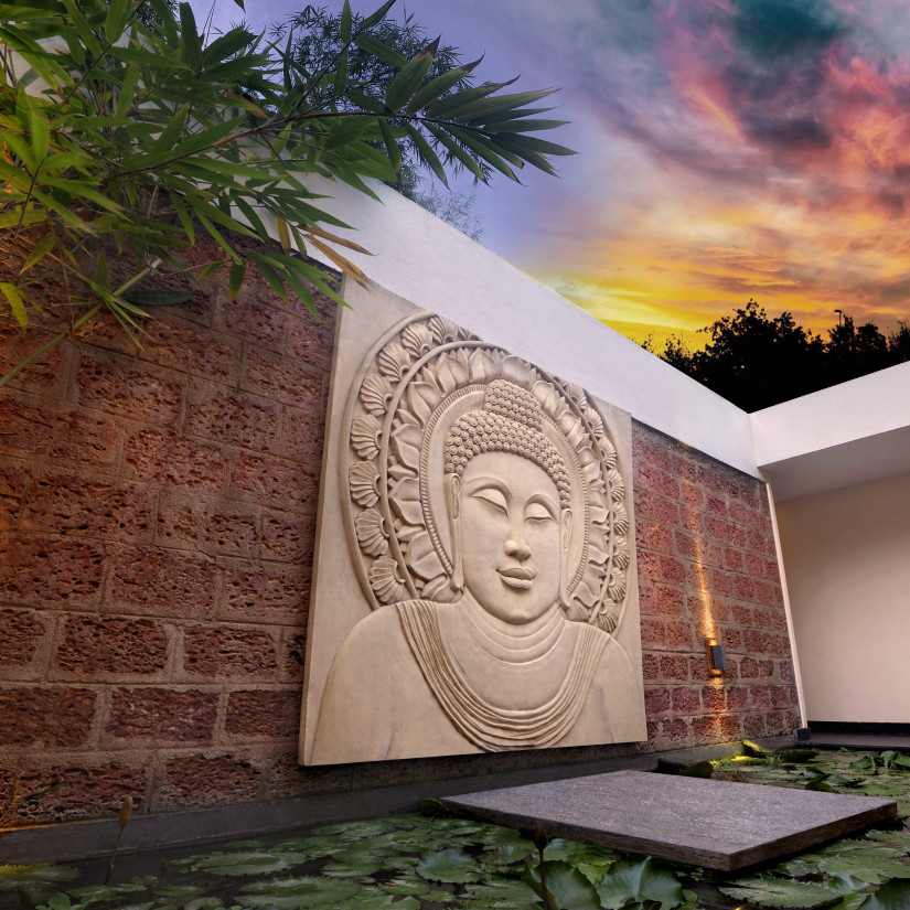 Artistic Buddha wall sculpture with ambient lighting in an outdoor setting.
