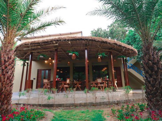 a view of outdoor restaurant with thatched roof at Themis Mudhouse, our nature resort near Delhi