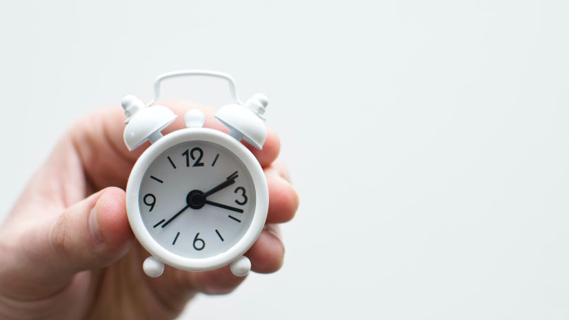 a hand holding a mini clock