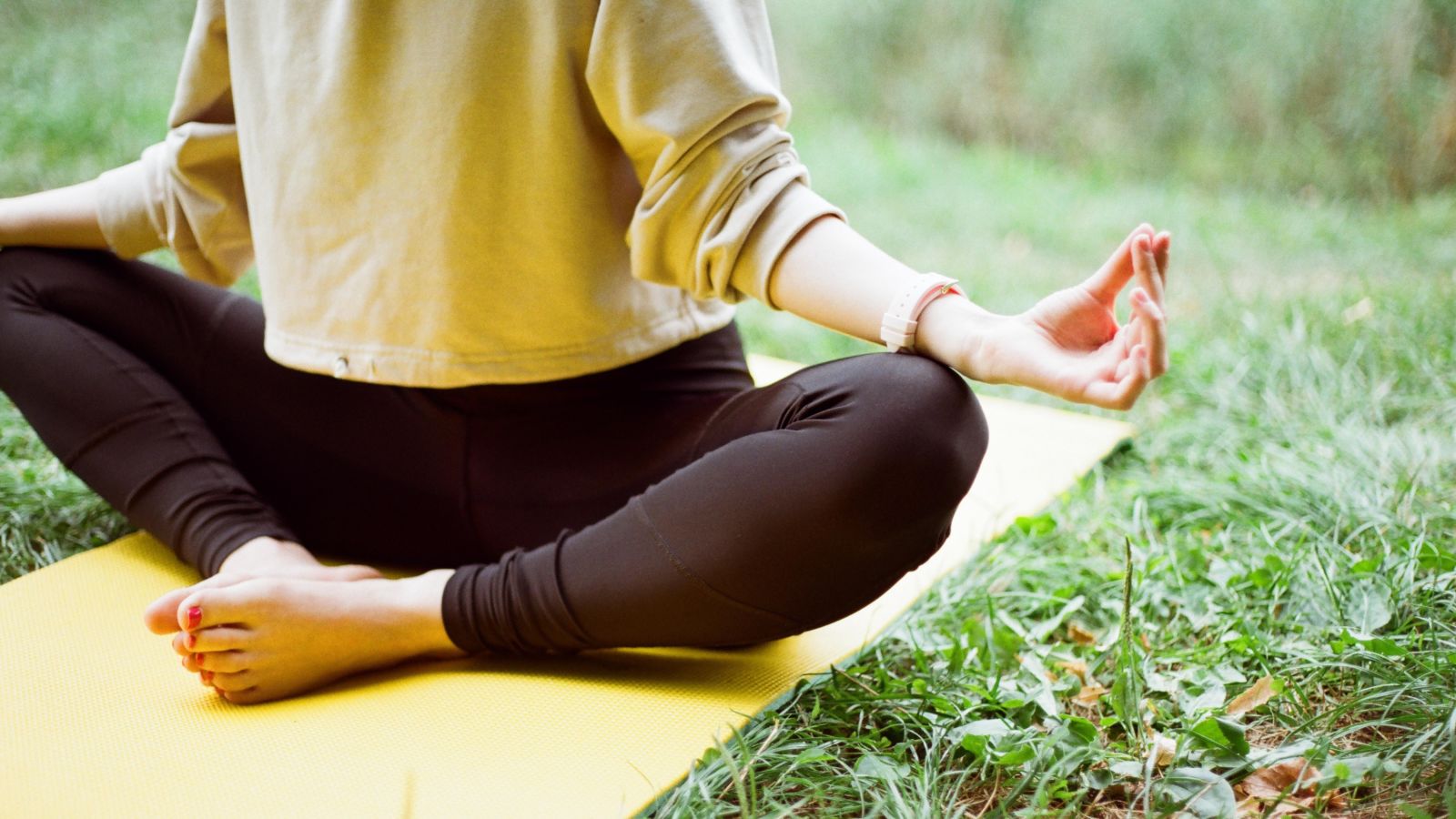 a person doing yoga on a grassy field during daytime