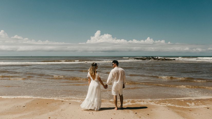 Couple looking at each other while holding hands at the beach