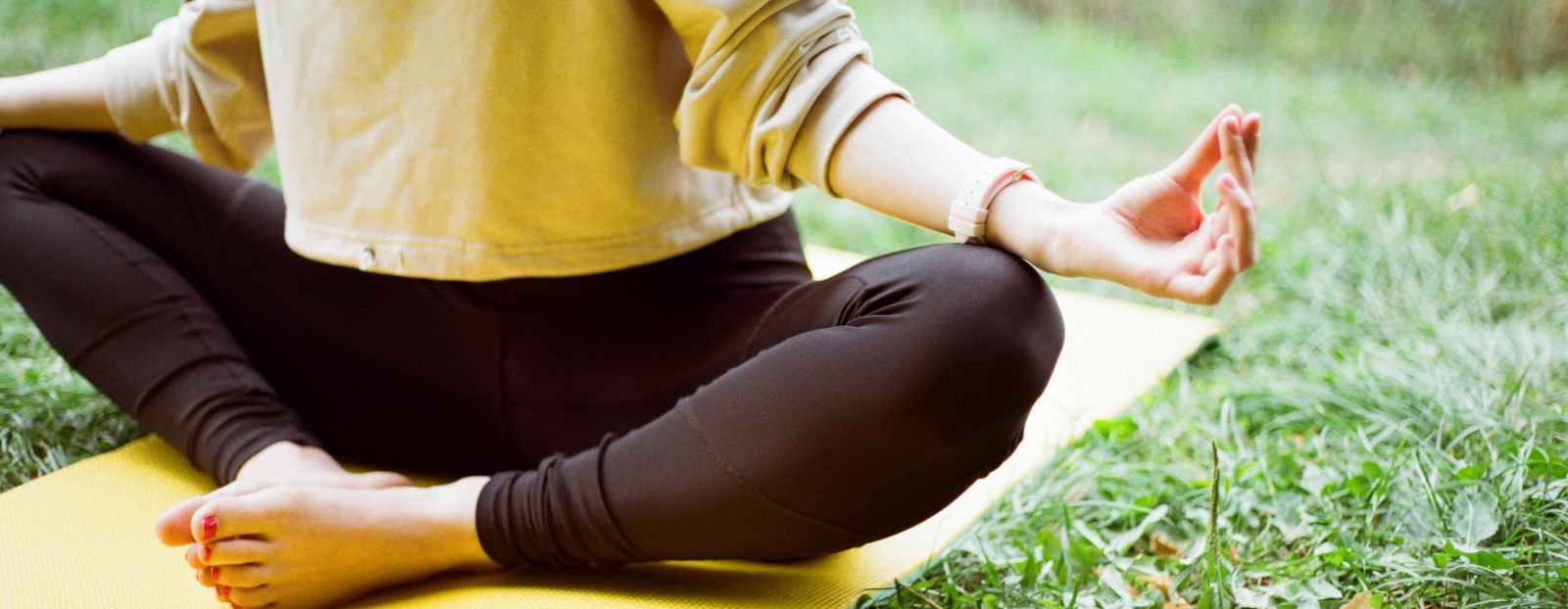 a person doing yoga on a grassy field during daytime