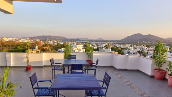 roof top Restaurant with tables and chairs with a hill in the background - - Maan Vilas by Stone Wood, Udaipur