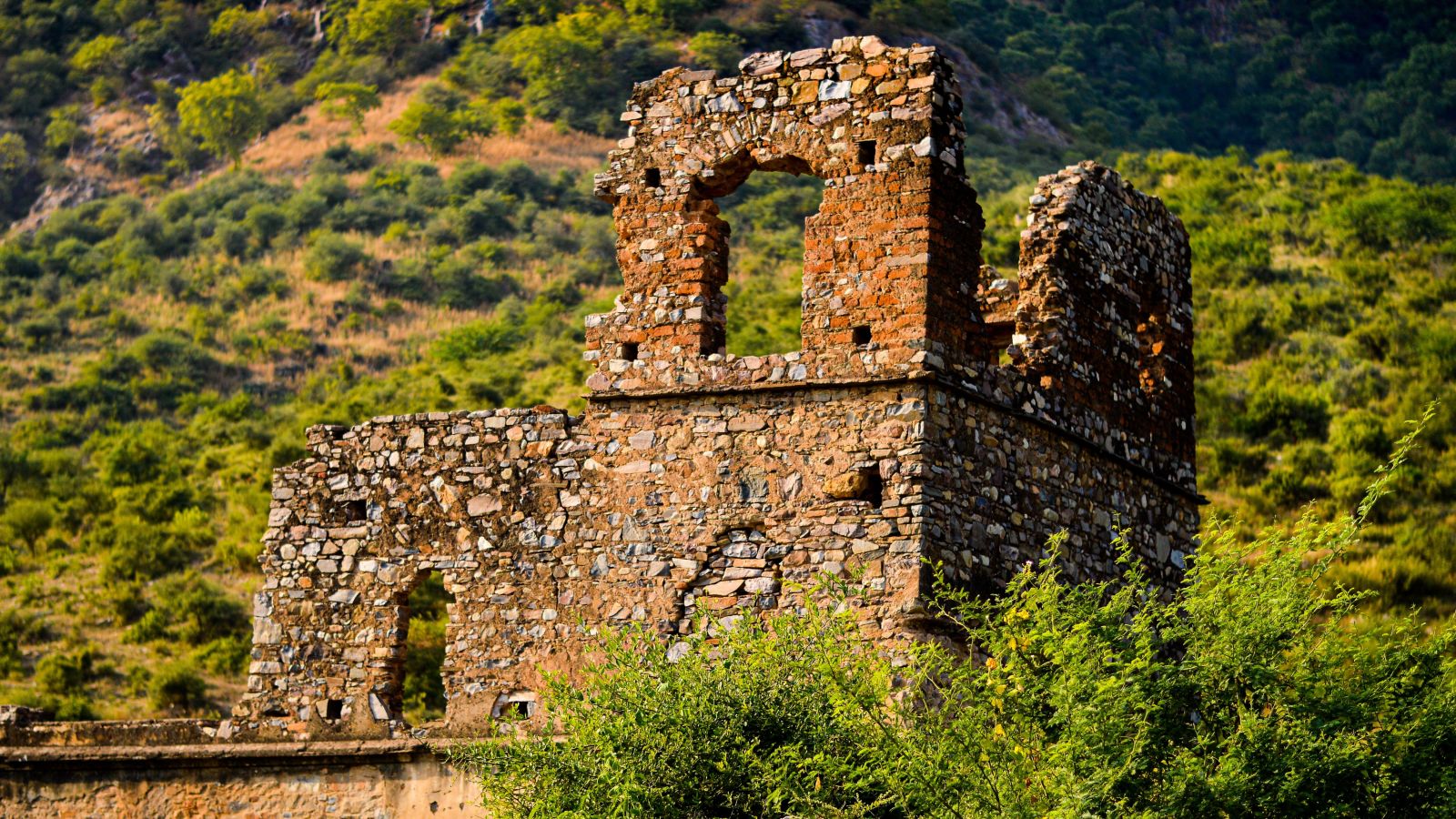 A fort in ruin with the backdrop of a hill surrounded by nature