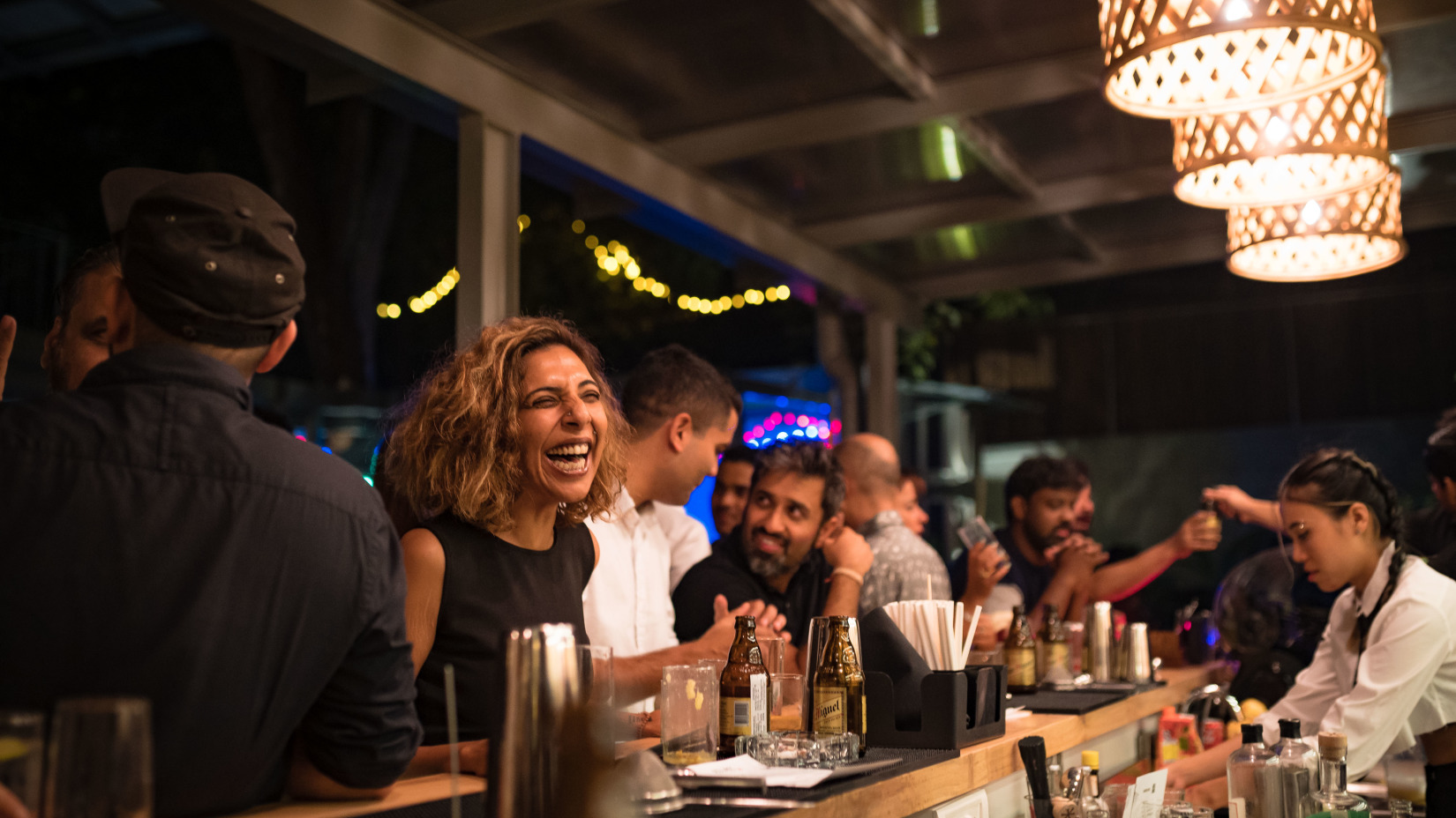 a group of people talking and having fun at a bar in Goa - Villa in Palms by V Escapes