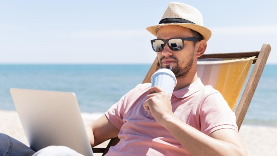 A man having a drink while working on a beach