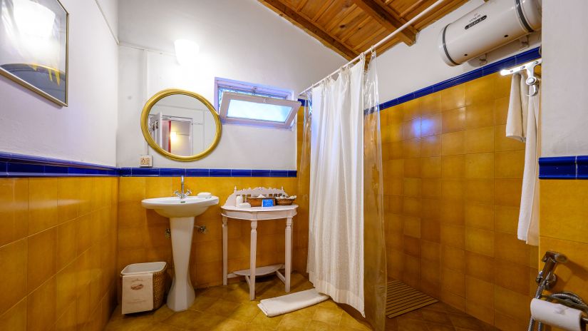 The Ramgarh Bungalows - a yellow themed bathroom with wash basin and water heater with separate shower space