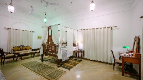 Deo Bagh - 17th Century, Gwalior - the bedroom area along with a sofa set kept on one side of the bed and a dressing table on the other side at the Sakhya Raja Mahal